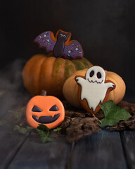Gingerbread in the style of Halloween. Ghost, pumpkin, bat. The creative power of the smoke. Dark mood. Wooden background. copy space. Vertical orientation