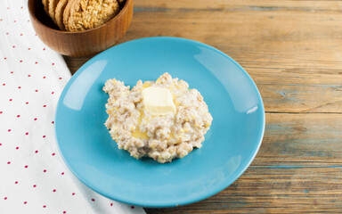 Breakfast: Healthy food classic porridge in blue dish on wood background. oatmeal food breakfast. Top view.