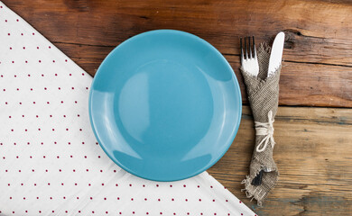 Top view of kitchen cutlery setting with polka dot napkin on grunge restaurant table.