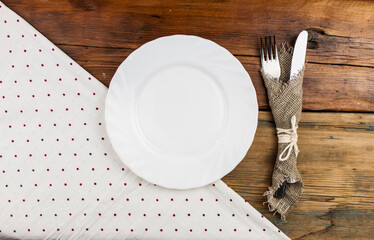 Top view of kitchen cutlery setting with polka dot napkin on grunge restaurant table.