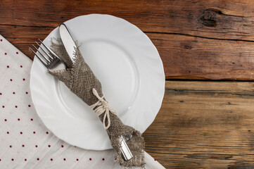 Top view of kitchen cutlery setting with polka dot napkin on grunge restaurant table.