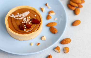 nougat or caramel filling tart with nuts (whole almond) on blue plate, french confectionery, copy space