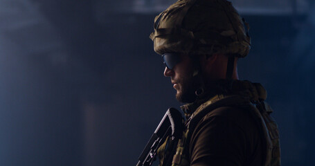 Fototapeta na wymiar Military man aiming gun in dark hallway