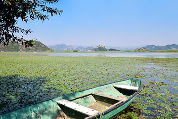 Naklejka na ściany i meble Old boat on the waves of Skadar lake in Montenegro on a background of mountains