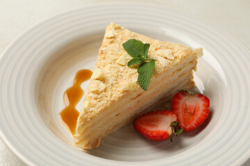 Plate with delicious Napoleon cake on white - gray background