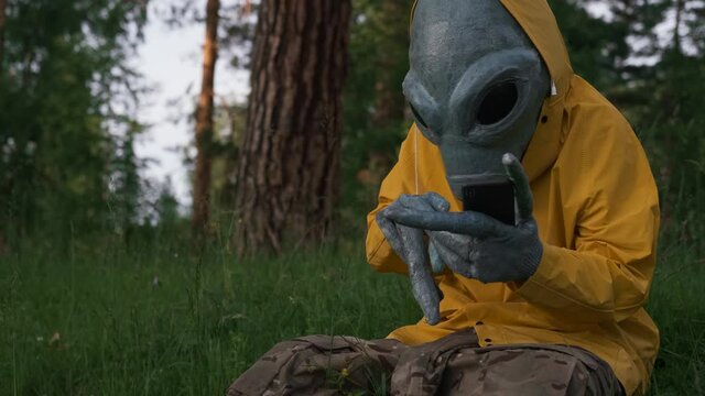 alien in yellow suit in forest talking on the phone, UFO concept, space, alien.