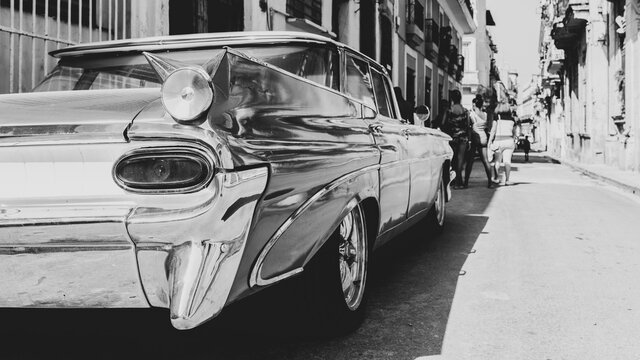 Black and white image of a vintage American car parked in Havana Vieja, Cuba. Selective shallow depth of field.