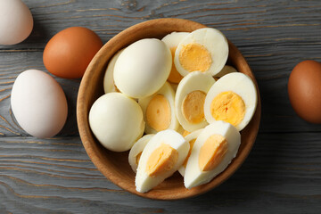 Bowl with boiled eggs on wooden background, top view