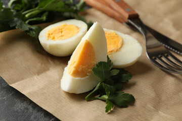 Baking paper with boiled eggs, parsley and forks on black smokey background