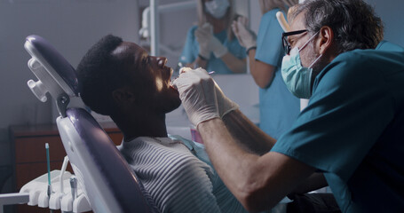 Dentist checking teeth of black patient