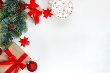 New Year's gifts with a red bow, a fir branch, a cup of coffee with marshmallows on a light background. Flat lay, top view, copy space for text. Christmas festive composition.