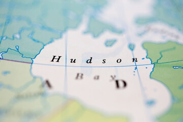 Shallow depth of field focus on geographical map location of Hudson Bay off coast of Canada on atlas