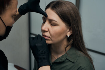 Fototapeta premium Permanent eyebrow makeup procedure. Eyebrow tattooing, process. The use of tools by a master for permanent eyebrow makeup.