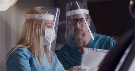 Professional dental specialist in masks discussing patient jaw