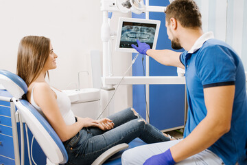 A dentist showing  photo of teeth to the patient on screen