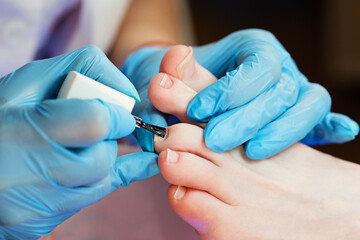 Process pedicure close up. Unrecognizable people. Master chiropody applying gel nail polish. Spa. Concept body care.