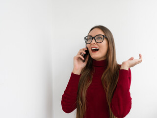 Young woman with glasses talking on the phone on a white background. Communication concept. Copy space