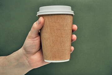 Paper cup in hand on a colored background. Eco-friendly materials in a coffee shop, biodegradable disposable tableware. Close up