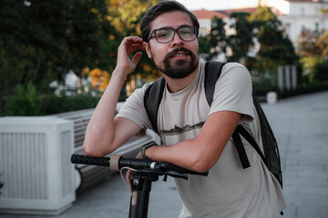 Attractive man riding a kick scooter at cityscape background.