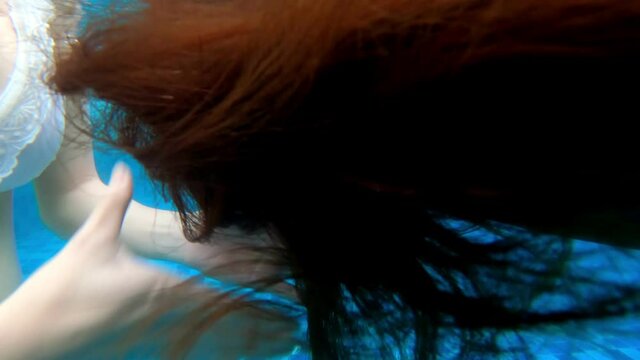 dark long hair moving under water. woman hair flying under swimming pool.