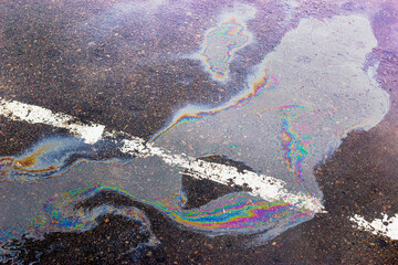 Colorful gas stain on wet asphalt. Oil stain caused by a leak under a car or truck.