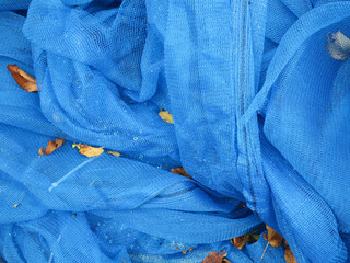 bundle of blue colored fabric covered with autumn leaves