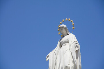 Fototapeta premium Virgin Mary is Queen of heaven. Antique statue against blue sky.