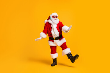 Full size photo of funky santa claus with grey beard listen magic x-mas christmas music headset dance party wear cap headwear sunglass isolated bright shine color background