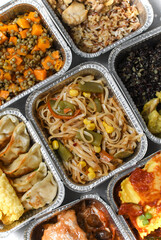 Takeout coronavirus food. Different aluminium lunch box with ravioli, curry chicken  rice, gyoza tempura, noodles vegetables, lentils with pumpkin. covid-19 takeaway  food delivery.