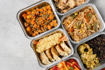 Takeout coronavirus food. Different aluminium lunch box with ravioli, curry chicken  rice, gyoza tempura, noodles vegetables, lentils with pumpkin. covid-19 takeaway  food delivery.