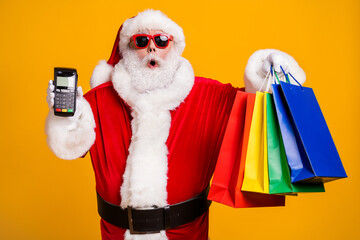 Portrait of his he nice attractive amazed astonished fat Santa holding in hands things digital terminal store boutique pay-pass black Friday isolated bright vivid shine vibrant yellow color background