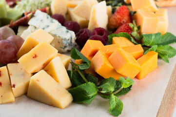 A varied set of cheese with fruits: raspberries, flower beds, figs.