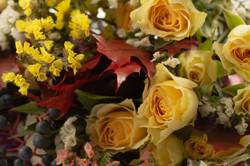 Floral background in autumn colors, from yellow roses, oak leaves, small delicate flowers and berries.