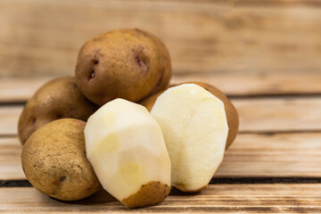 peeled potatoes in the foreground on a wooden background.