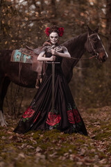 Young woman dressed as mexican symbol of day of the dead posing in forest with horse