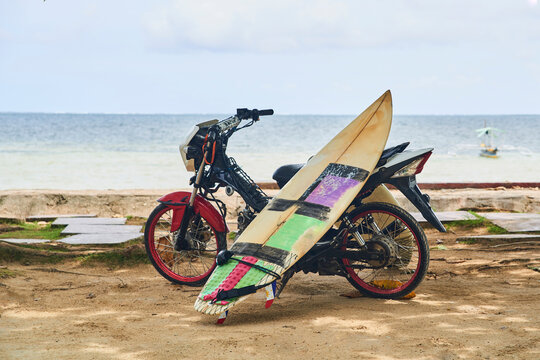 Short surf board leaning in a motorcycle with the seaside as background