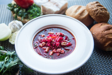 Delicious beet soup in a plate. Traditional Ukrainian Russian soup (borsch) with herbs, bread and sour cream. Side view..