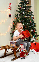 Happy child boy opens a gift next  to the Christmas tree. Concept of the New Year .Merry Christmas.