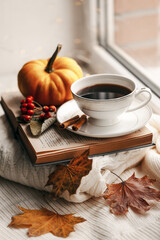 Still life of knitted woolen items, a cup of coffee and pumpkin. Dry leaves. Thanksgiving Day. Book. Morning. Fall. The concept of a cozy home holiday.