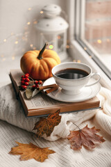 Still life of knitted woolen items, a cup of coffee and pumpkin. Dry leaves. Thanksgiving Day. Book. Morning. Fall. The concept of a cozy home holiday.