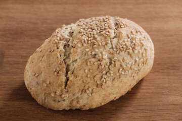 Ein traditionell handwerklich gebackenes Sesam-Brötchen auf einem Holztisch