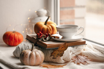 Still life of knitted woolen items, a cup of coffee and pumpkin. Dry leaves. Thanksgiving Day. Book. Morning. Fall. The concept of a cozy home holiday.