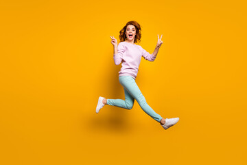 Fototapeta na wymiar Full body photo of cheerful crazy excited woman enjoy spring vacation holiday jump make v-sign scream rejoice wear casual style clothes isolated over yellow color background