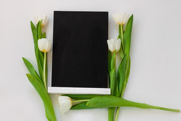 Black chalk board mockup with tulip flowers on white background. Blackboard menu with easel, spring sales. Copy space frame ad text content. Blank inscription template. Education advertisement display