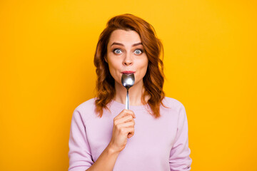 Portrait of astonished inspired girl have weekend in restaurant taste dish enjoy lick spoon impressed stare stupor wear pink jumper isolated over yellow color background - obrazy, fototapety, plakaty