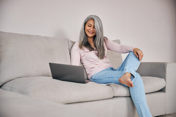 Beautiful woman freelancer looking to the screen her computer while surfing internet at home