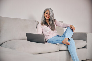 Obraz premium Beautiful woman freelancer looking to the screen her computer while surfing internet at home