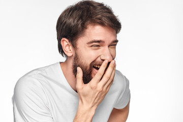 Fototapeta premium cheerful bearded man in a white t-shirt emotions gestures with his hands light background studio