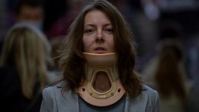Close-up portrait of a middle-aged woman wearing a bandage around her neck. It is located in a public place.
