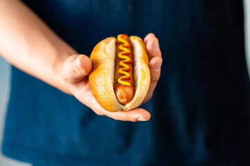 Hand hold American fast food Hotdog with fresh organic bread bun white wheat and black charcoal...